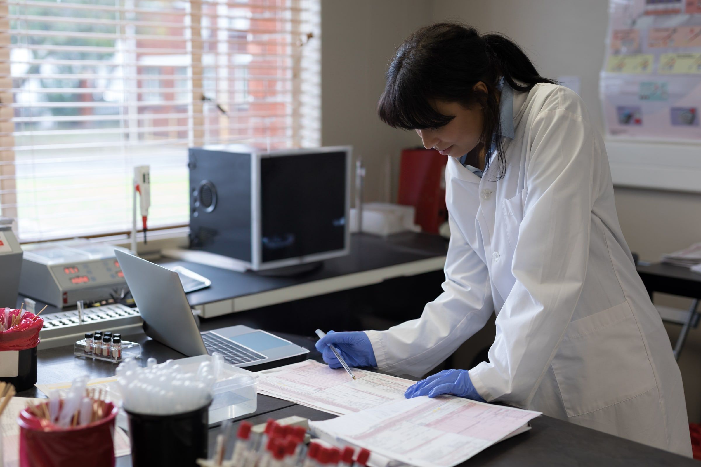 Lab technician reviewing requisition paperwork at a lab bench