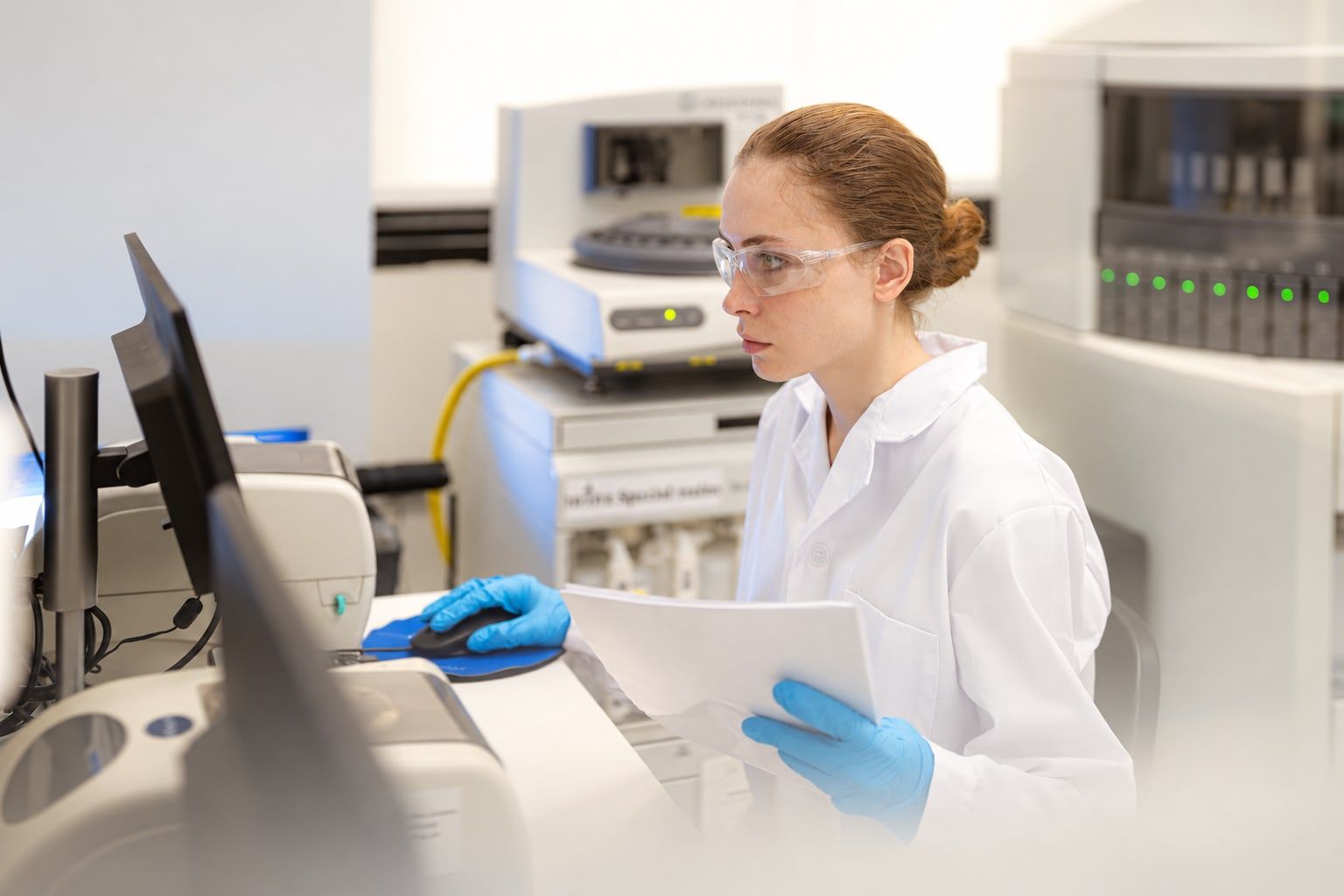 Lab scientist reviewing printed results at a workstation